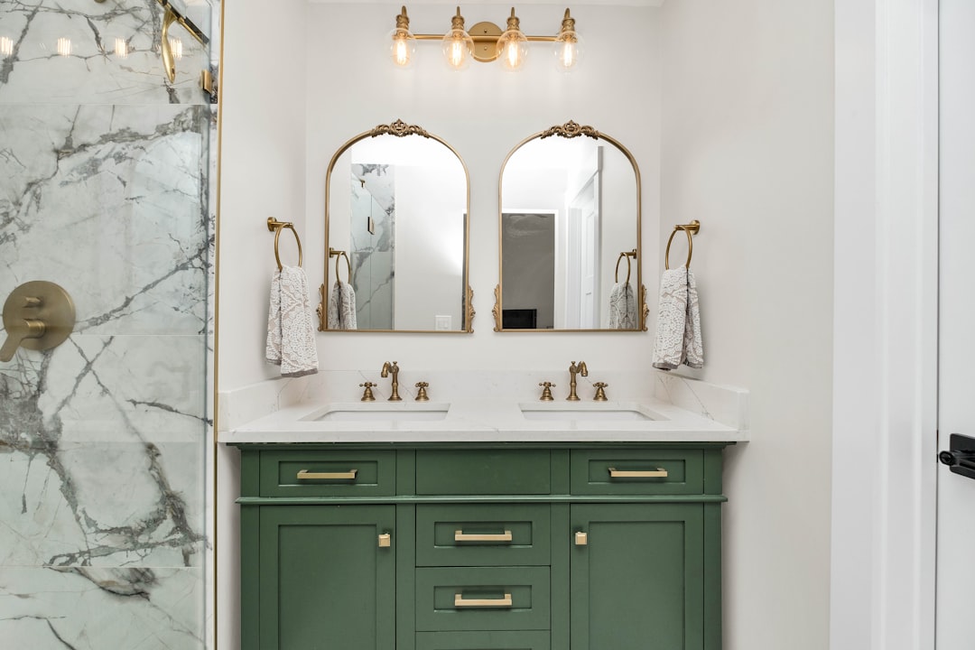 a-bathroom-with-marble-counter-tops-and-green-cabinets-fpim6zlm6fc